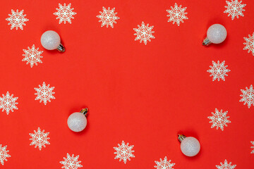 Xmas pattern. White snowflakes, silver balls in Christmas composition on red background for greeting card. Flat lay, top view, copy space.