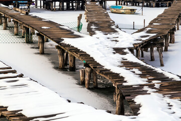 Wooden piers on the frozen lake and an orphaned frozen boat in the distance