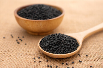 Close up shot ,Black sesame seeds in wooden spoon on the sackcloth background.