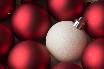 original and different on christmas is an attitude.
a glittered white Christmas Decoration Balls stands out from a group red balls. originality. Originality and attitude. horizontal close up