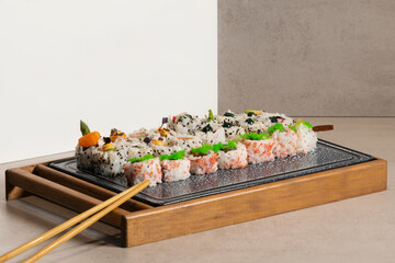 view of an assortment of appetizing uramaki pieces on a tray with wooden chopsticks