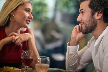 beautiful young couple talking at dinner, looking each other, smiling. copy space in between