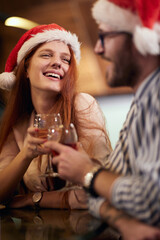 drunk caucasian redhead with santa hat toasting with her partner at new year celebration