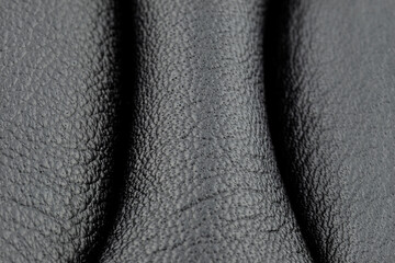 A macro shot of black leather with blue stitching on the sides.