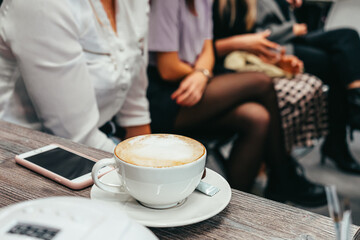 Fragrant cup of cappuccino and a phone on the table