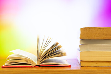 A pile of books and open book with blurred colour as background and copy space