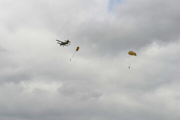 Skydivers jump from an old biplane plane on a cloudy day