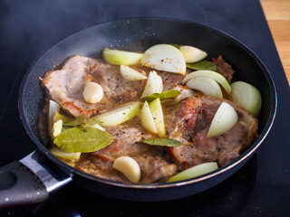 Pork steaks in frying pan with onion
