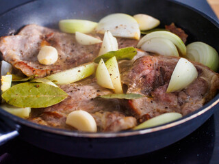 Pork steaks in frying pan with onion
