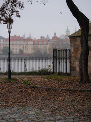 View from Kampa Island along Charles Bridge toward Prague's Old Town on a foggy autumn morning