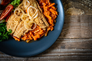 Fish dish - fried fish fillet on vegetable sauce on wooden table
