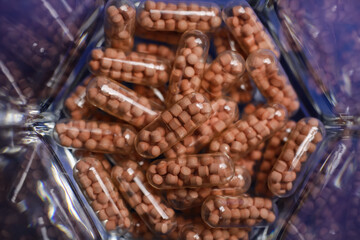 Macro close up of transparent capsules with pearls on bottom of drinking glass (focus on center)