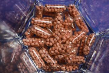 Macro close up of transparent capsules with pearls on bottom of drinking glass (focus on center)