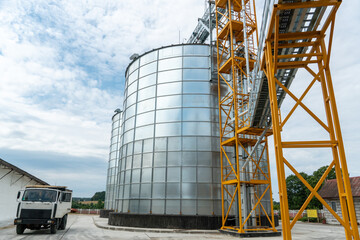 Obraz premium silver silos on agro manufacturing plant for processing drying cleaning and storage of agricultural products, flour, cereals and grain. Large iron barrels of grain. Granary elevator