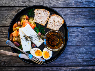 Soft boiled eggs with Greek salad served on wooden table 