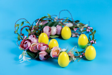Colored Easter wreath and plastic eggs on a blue background