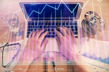 Double exposure of man's hands typing over laptop keyboard and forex chart hologram drawing. Top view. Financial markets concept.