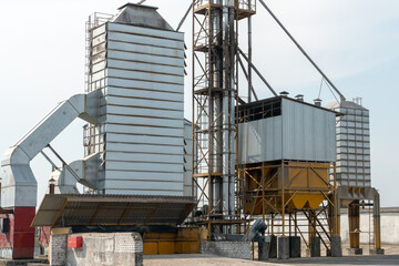 silver silos on agro manufacturing plant for processing drying cleaning and storage of agricultural products, flour, cereals and grain. Large iron barrels of grain. Granary elevator