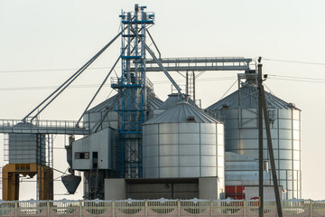 silver silos on agro manufacturing plant for processing drying cleaning and storage of agricultural products, flour, cereals and grain. Large iron barrels of grain. Granary elevator