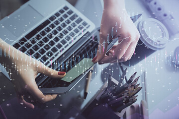 Double exposure of businesswoman hands typing on computer and financial graph hologram drawing. Stock market analysis concept.