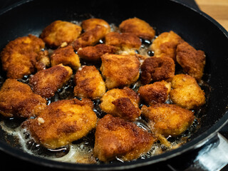 Chicken breast nuggets frying in pan
