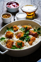 Chicken nuggets with rice and vegetables on wooden table
