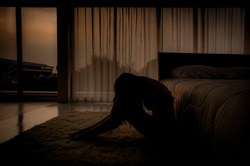 young woman sitting on the floor in the  bedroom feeling sad and  depressed in the evening. Suffer...