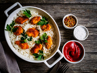 Chicken nuggets with rice and vegetables on wooden table
