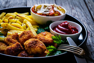 Fried breadcrumb chicken nuggets with French fries and vegetables
