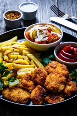 Fried breadcrumb chicken nuggets with French fries and vegetables
