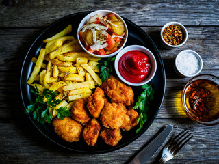 Fried breadcrumb chicken nuggets with French fries and vegetables
