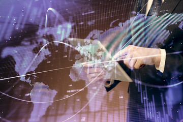 Double exposure of man's hands holding and using a digital device and forex graph drawing. Financial market concept.