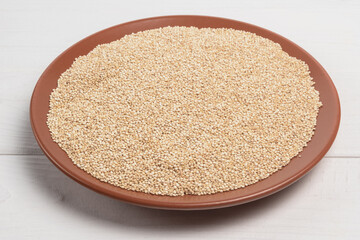 Quinoa in the brown plate on white wooden table. Close -up. Horizontal orientation.
