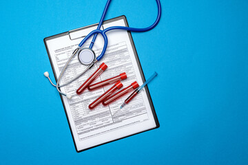Clipboard with paper blank form with medical tools on blue background with cope space