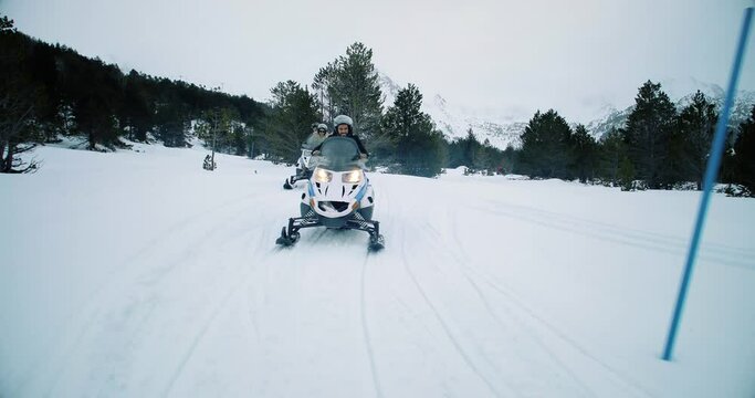Snowmobiles on snowy road in the forest. Group of friends doing perfect leisure mountain activity 4K