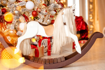 Fototapeta na wymiar The horse rocking kids chair, classic new year tree with presents.