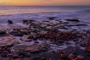 Several rocks on the beach in the warm light of a sunrise