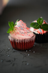 sponge cap cakes with cream of cream and cream cheese are decorated with mint leaves and sprinkled with sugar balls.