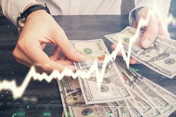 Multi exposure of financial graph drawing hologram and USA dollars bills and man hands. Analysis...