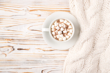 Close up top view photo of tasty beverage with white puffy soft marshmallow in cup standing on wooden desk with knitted fabric