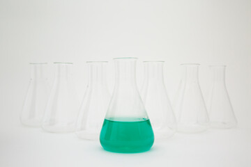 Scientific laboratory glass erlenmeyer flask filled with green liquid with glassware equipment on...