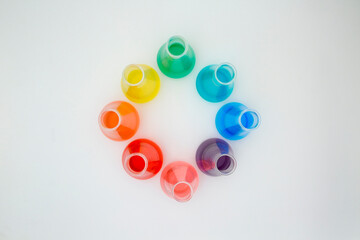 Scientific laboratory glass erlenmeyer flask filled with colorful liquid forming rainbow on white...
