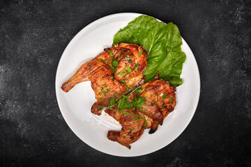 Fried chicken with a delicious crispy crust, with lettuce, on a white plate, on a black background
