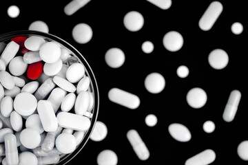 red pills in a glass bowl among the white pills top view