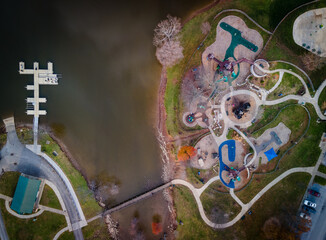 Obraz premium Aerial view of the playground next to Jacobson park lake in Lexington, Kentucky with pedestrian bridge leading to paddle boats dock next to it