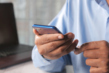 Close up of young man hand using smart phone.