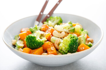 Vegetable salad bowl of broccoli, baked pumpkin, avocado and nuts. Healthy vegan food