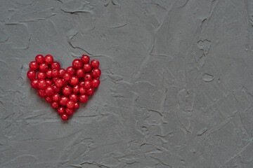 Red heart of currants on a gray concrete background. Heart shaped berries. Valentine's Day.