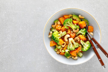 Vegetable salad bowl of broccoli, baked pumpkin, avocado and nuts. Healthy vegan food