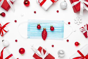 Coronavirus Christmas concept. Face mask in frame made of Christmas gift boxes and decorations on white background
